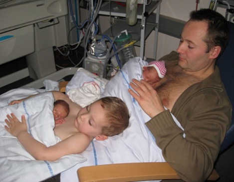 O pequeno gémeo prematuro está deitado no peito de seu irmão mais velho. Mas há muito mais nesta foto.